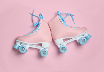 Pair of stylish quad roller skates on color background, top view