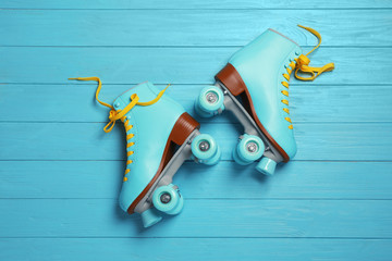 Pair of stylish quad roller skates on wooden background, top view