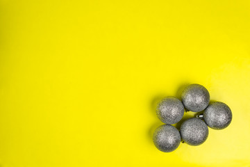 Five silver Christmas baubles lies on a yellow background with copy space, christmas decorations.
