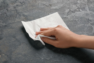 Woman wiping grey table with paper napkin, closeup © New Africa