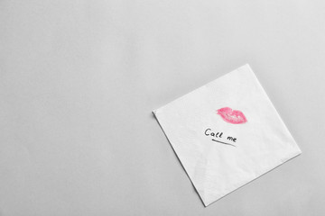 Paper napkin with lipstick mark and words CALL ME on grey background, top view. Space for text