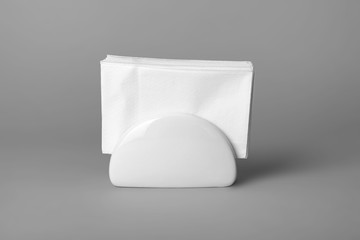 Ceramic napkin holder with paper serviettes on gray background