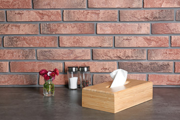 Composition with wooden napkin holder on table near brick wall