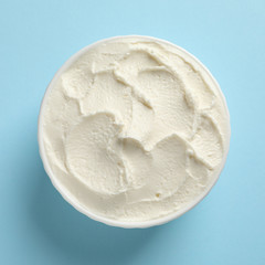 Bowl of tasty cream cheese on color background, top view