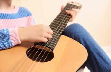 Fototapeta premium Little girl playing wooden guitar, closeup view