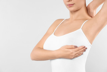 Woman checking her breast on white background, closeup