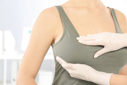 Doctor checking woman's breast at hospital, closeup