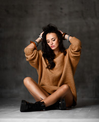 Young sexy blonde fashion woman sitting on floor in brown knitted blouse 