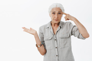 Waist-up shot of irritated smart elderly woman being pissed with son making stupid mistake rolling...