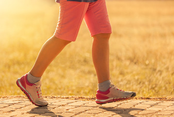 Close up movement woman feets walking on the road in sunset time