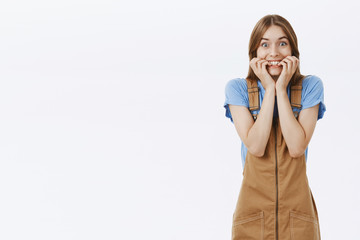 Portrait of surprised happy woman gazing with anticipation and joy biting fingernails and smiling...