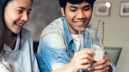 Friends are smiling, happy partying in the bar and talking and clinking bottles with beverages.