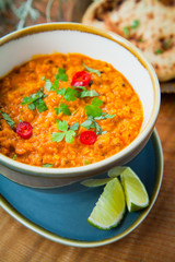 Red lentils Dal with coconut milk, lime and tomatoes and fesh chili garnish. Indian cuisine.