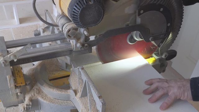 Construction worker using slider compound mitre saw or circular saw for cutting massive wood board. Details of construction, renovation works