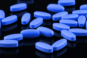 blue pills on a black background - obrazy, fototapety, plakaty