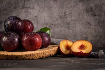 Fototapeta na wymiar Red plums in a cork plate