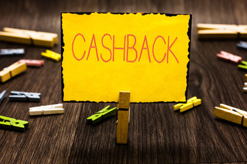 Handwriting text Cashback. Concept meaning incentive offered to buyers certain products whereby receive cash Clothespin holding yellow paper note several clothespins wooden floor