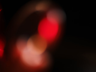 Blurred background lights. Abstract defocused gold, white, red and yellow glitters texture on black background. Shining glowing snow effects.