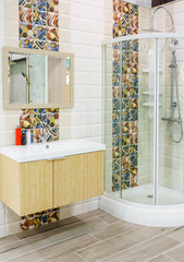 Bright new bathroom interior with glass walk in shower with white tile surround, toilet, bidet, basin and large mirror