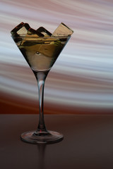 Cocktail glass with a drink and ice cubes in the neon light of a nightclub