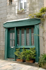 Fototapeta na wymiar Ville de Granville, façade verte d'un vieux commerce de la Haute Ville et jardinières de fleurs, département de la Manche, France