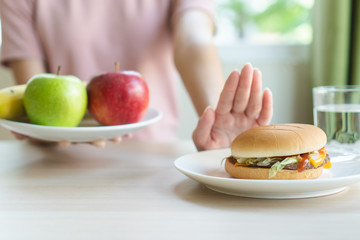 Woman on dieting for good health concept. Woman doing cross arms sign to refuse junk food or fast food (hamburger and potato fried) that have many fat.