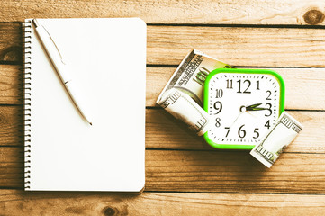 Clock, money, pen and notebook on a wooden background. Time Management. Top view