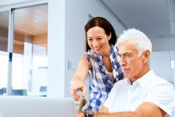 Happy modern mature couple working on laptop at home