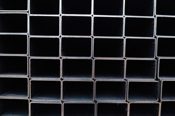 Bent metal profile channel background. Steel materials, construction supplies. Coated profiles in the rack. Metal profile pipe of rectangular cross section in packs at warehouse