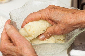 Preparation steps of traditional Colombian dish called stuffed potatoes: Kneading the mashed potatoes by hand to form a dough for the stuffed potatoes