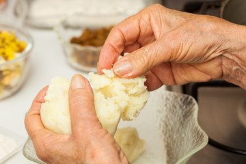 Preparation steps of traditional Colombian dish called stuffed potatoes: Kneading the mashed potatoes by hand to form a dough for the stuffed potatoes