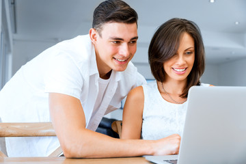 Obraz premium Happy modern couple working on laptop at home