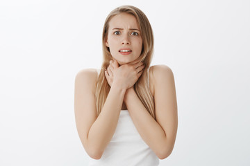 Fototapeta premium Girl got ill before important date, holding hands on neck looking worried suffering pain in throat, getting sick, frowning nervously and displeased, staying at home to cure cold over gray background