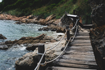 Fototapeta na wymiar Wood small bridge walk way for sightseeing beside beach with green nature around.