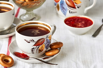 A cup of black tea with bagels and strawberry jam       