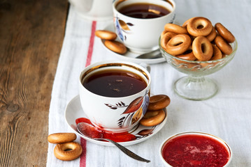 A cup of black tea with bagels and strawberry jam       