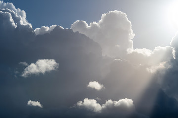 Dramatic dark cloudy sky, white clouds backlit by sun moving across the sky, sun rays streaming down, nature background