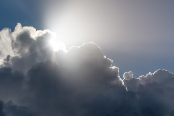 Dramatic dark cloudy sky, white and gray cumulus clouds moving across the blue sky and sun rays streaming out, nature background