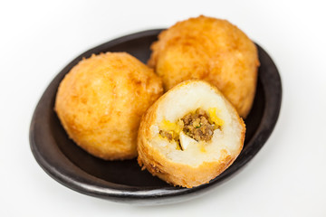 Preparation steps of traditional Colombian dish called stuffed potatoes : Ready stuffed potatoes served in a black ceramic dish isolated on white background