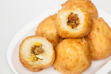Preparation steps of traditional Colombian dish called stuffed potatoes : Ready stuffed potatoes served in a white ceramic dish isolated on white background