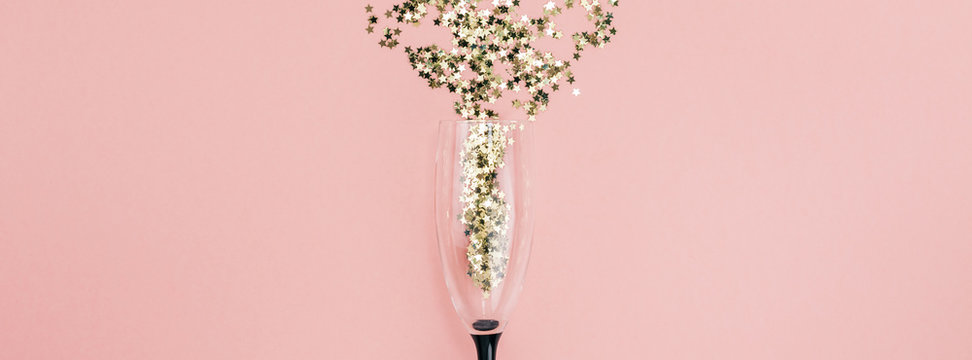 Champagne glass poured out golden stars confetti