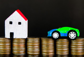 House and car on stack of coins on black background