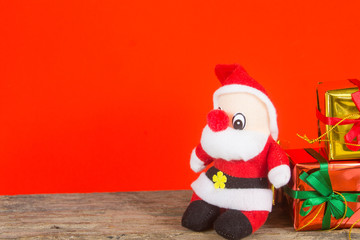 gift box and santa claus doll on the wooden table with red background