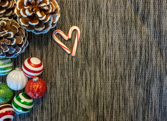 Candy Cane Forming a Heart With Pine and Ornaments on Dark Background