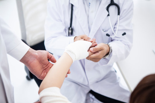 手を怪我した患者に包帯を巻く医師