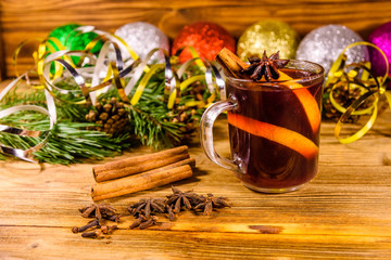 Cup of mulled wine with cinnamon, christmas decorations and fir tree branches on wooden table