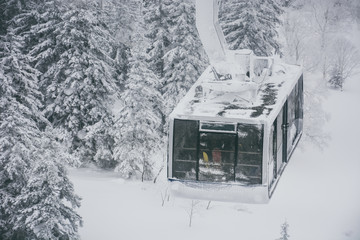 group of tourist and  skiers carries skis and equipments in cable car to the track on a slope for skiing on Mount Asahi (Asahidake mountain) during snowfall on winter day, Hokkaido, Japan © iamtui7