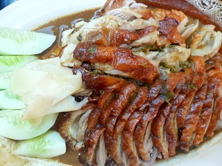 Chinese food style, Top view of roasted duck with cucumber and pickled ginger on plate in restaurant, Sliced peking duck as a background