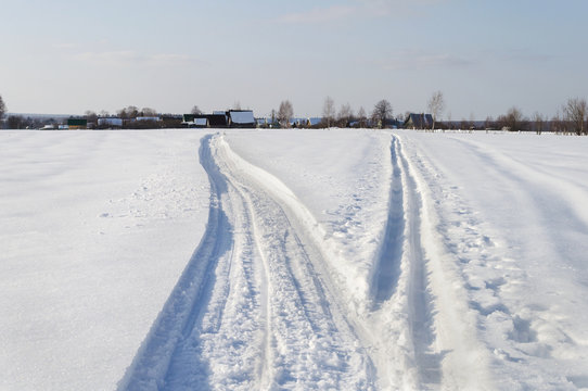 Winter landscape with small village, tracks in snow