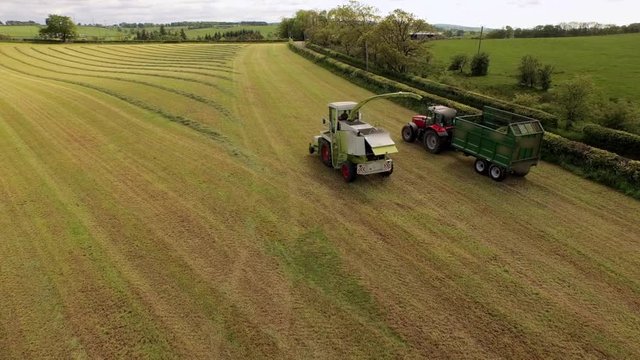 Aerial View Harvester Driving Alongside Tractor with Trailer in Field